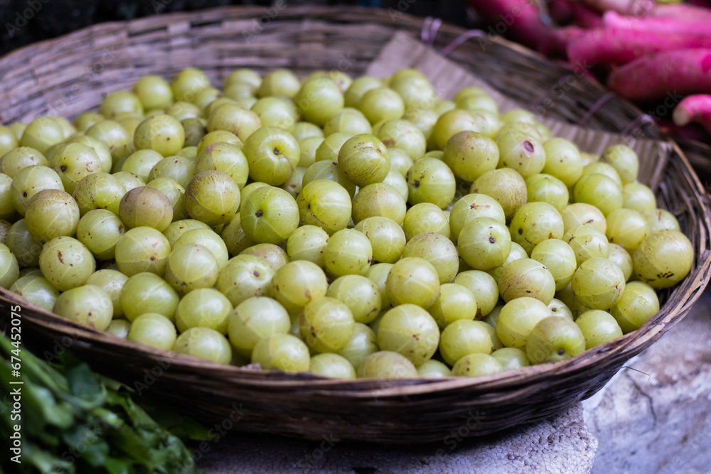 Indian gooseberry or amla or amlaki kept in cane basket for selling in market. It is great source of vitamins and has health benefits.