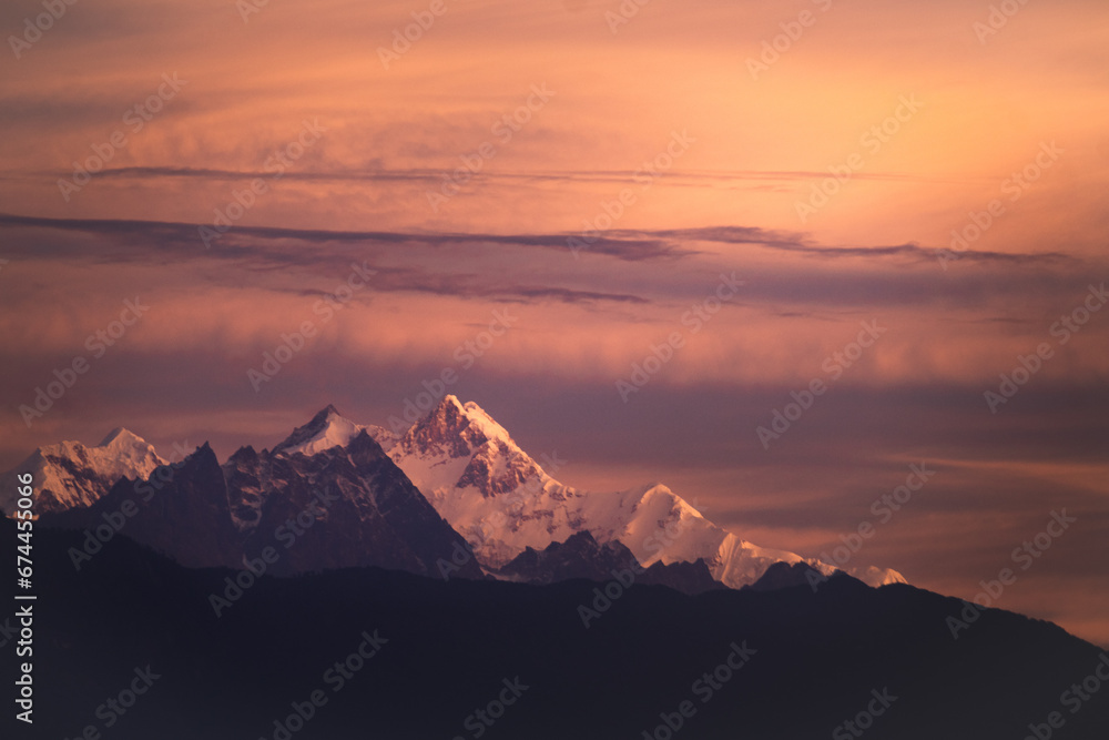 Mount kangchenjunga peak of Himalayan mountains during sunrise. Snow clad golden white peaks under cloud cover as seen fro kalimpong india.