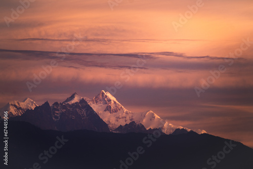 Mount kangchenjunga peak of Himalayan mountains during sunrise. Snow clad golden white peaks under cloud cover as seen fro kalimpong india.
