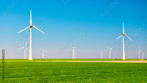 Windmill turbines in the Netherlands, wind mill turbines with a green meadow in front