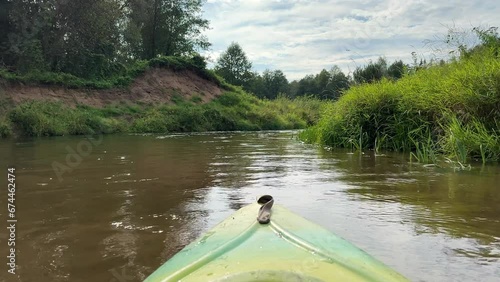 Kayaking on a river in Summer. Kayak's boat bow. Focus on beautiful scenery river with calm water route along green forest. No people. Watersport and recreational activity concept. photo