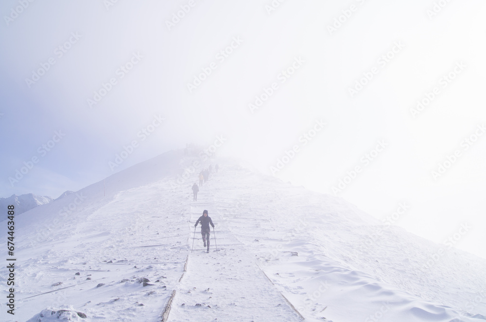 Serene Ascent in the Clouds: Hikers Embrace the Misty Mountain Trail on Kasprowy Wierch, a Surreal Journey through Ethereal Winter Landscape - Perfect for Adventure and Nature-Themed Projects.