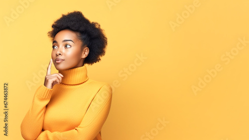 Portrait of cute interested african american lady touching her chin looking mockup empty space banner isolated yellow color background.