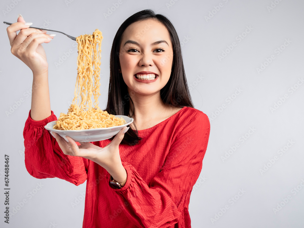 A portrait of a happy Asian woman wearing a red shirt, posing eating noodles. Isolated against a white background. A portrait of a happy Asian woman wearing a red shirt, posing eating noodles. Isolated against a white background.