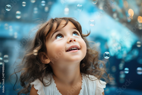 Happy brunette little girl excited looking up in the bubbles