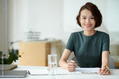 Portrait of female entrepreneur filling application form when working at office desk