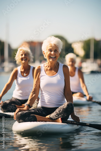 group of senior women doing yoga on sup board photo