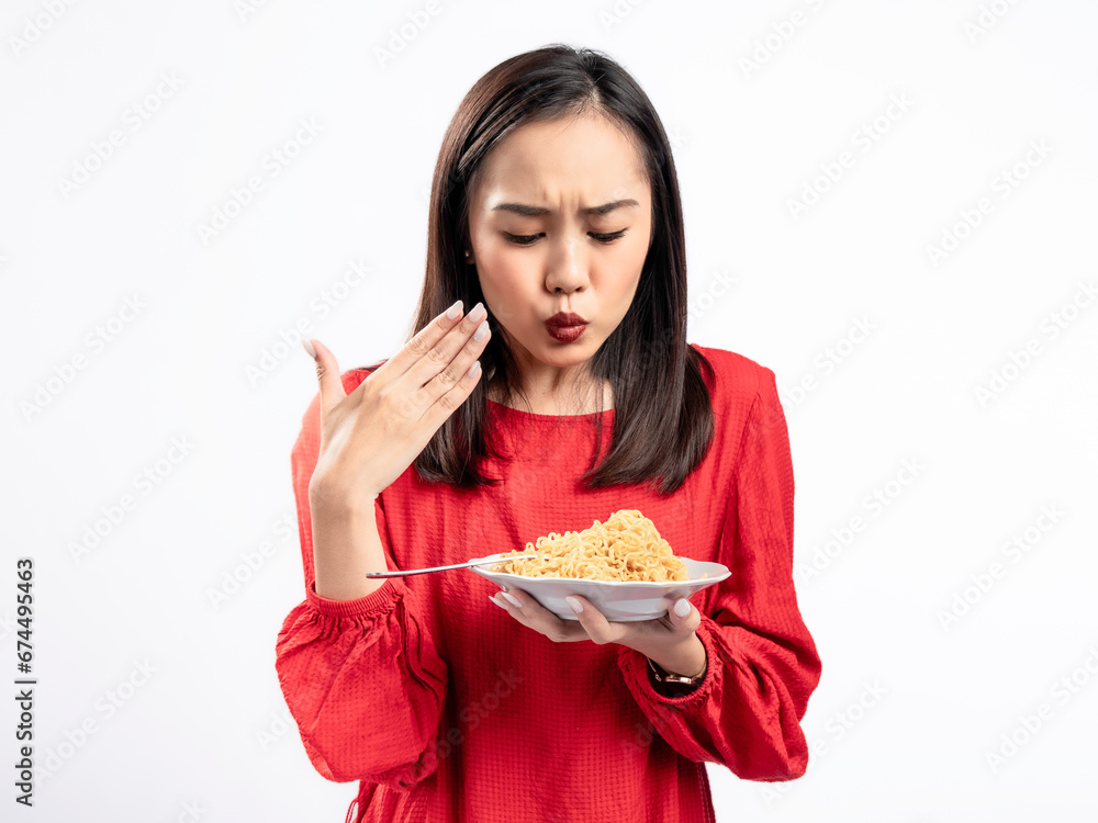 A portrait of a happy Asian woman wearing a red shirt, eating noodles, and feeling a bit spicy. Isolated against a white background. A portrait of a happy Asian woman wearing a red shirt, eating noodles, and feeling a bit spicy. Isolated against a white background.