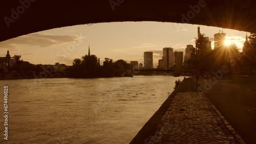 Wide angle sunset silhouette of the Frankfurt Skyline framed by Ignatz Bubis Bridge. Summer evening with people walking  photo