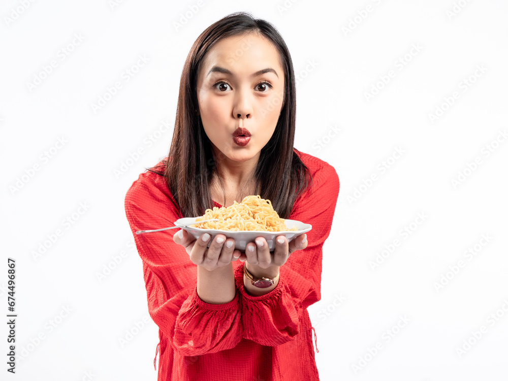 A portrait of a happy Asian woman wearing a red shirt, presenting noodles, and about to eat them. Isolated against a white background. A portrait of a happy Asian woman wearing a red shirt, presenting noodles, and about to eat them. Isolated against a white background.