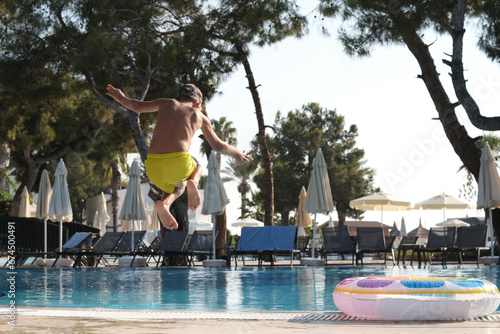 Capturing the essence of vacation: A spirited jump into crystalline waters with vibrant pool accessories © yavdat