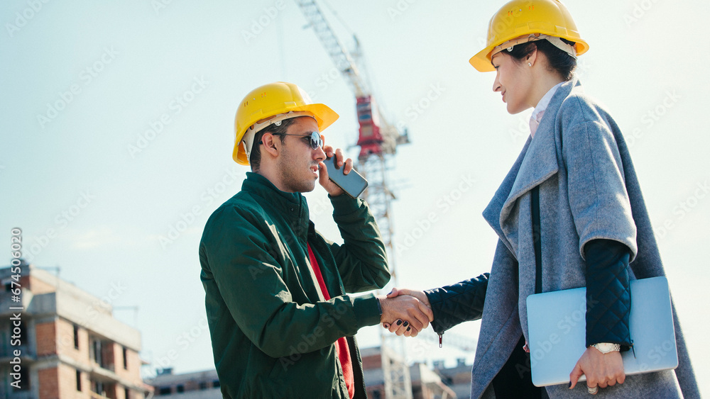 Two young engineers shaking hands at construction site Two young engineers shaking hands at construction site