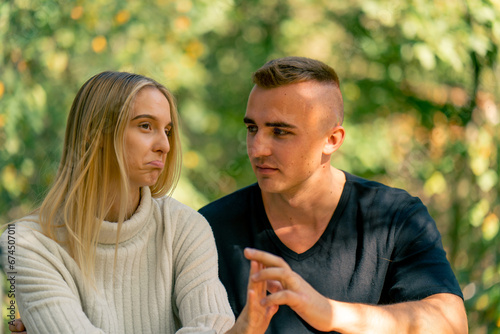 Obraz na plátne A young couple a guy and a girl are talking seriously while sitting together on