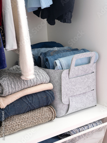 Felt baskets for storing things. Two felt boxes in the closet with neatly folded jeans and sweaters. Home storage system