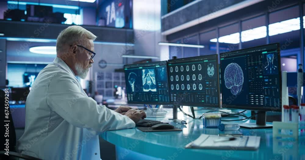 Senior Male Neuroscientist Using Desktop Computer To Analyze MRI Scans Of Brain In Medical