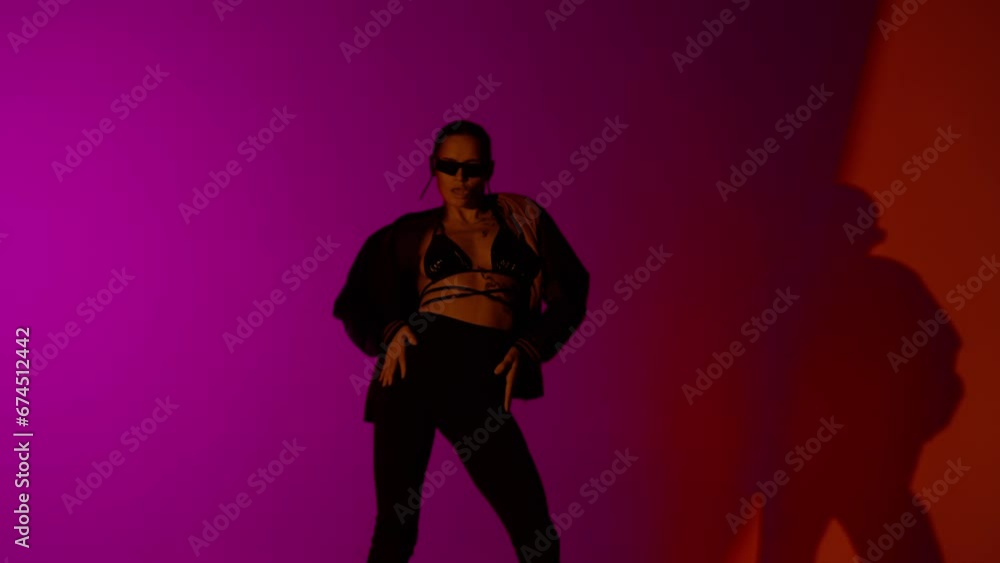 Appealing woman dancer dancing in jacket and on high heels in the studio, red and purple neon light vibrant background. Appealing woman dancer dancing in jacket and on high heels in the studio, red and purple neon light vibrant background.