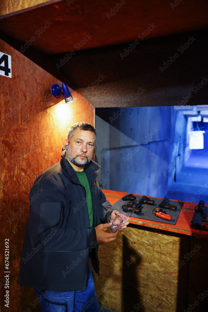 Man choose the pistol at firing range 