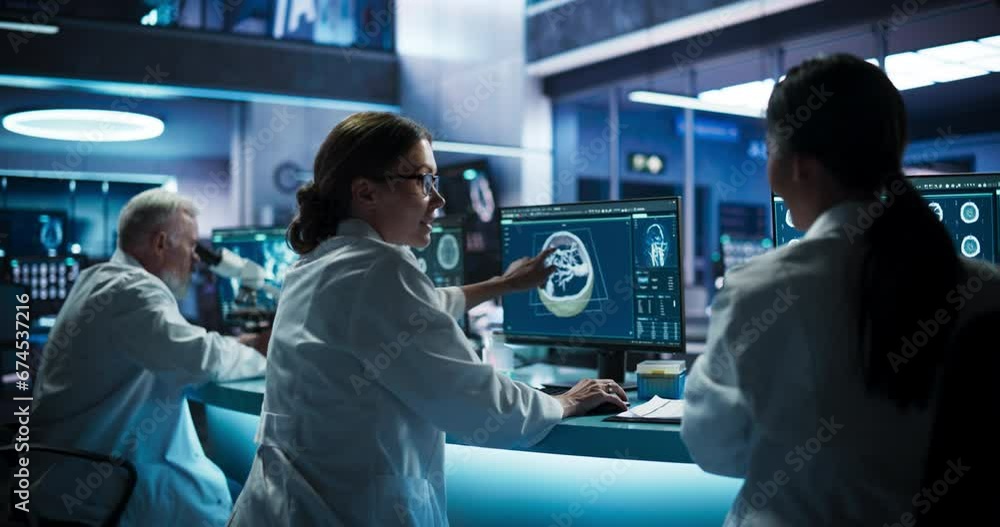 Back View Of Diverse Scientists Working In Medical Research Center. Male Doctor Using Microscope And His Female Colleagues Looking At 3D Software Visualization Of Patient's Brain After Stroke.