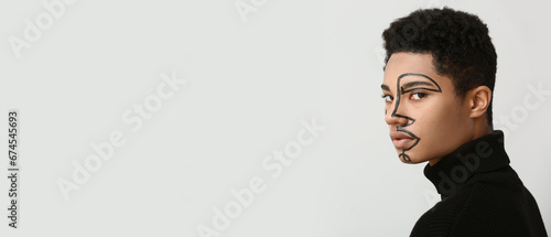 Young African-American guy with painted face on light background with space f...