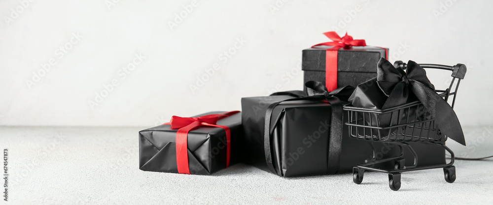 Naklejka premium Shopping cart with gifts on light background. Black Friday sale