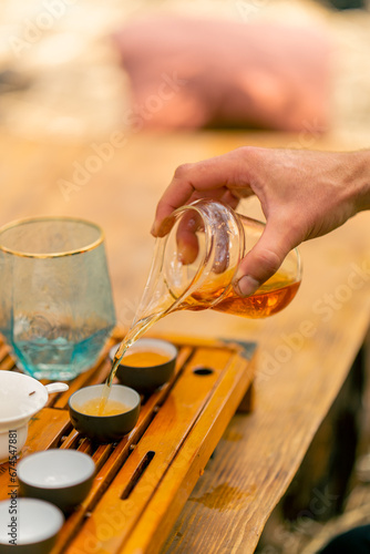 Close-up shot of brewed natural Chinese tea being poured into ceramic bowls during traditional tea ceremony