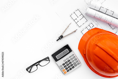 Calculator and construction helmet on architects desk, top view. Construction engineering