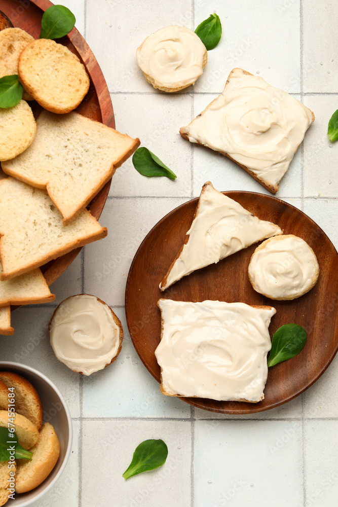 Plate of tasty toasts and croutons with cream cheese on white tile background Plate of tasty toasts and croutons with cream cheese on white tile background
