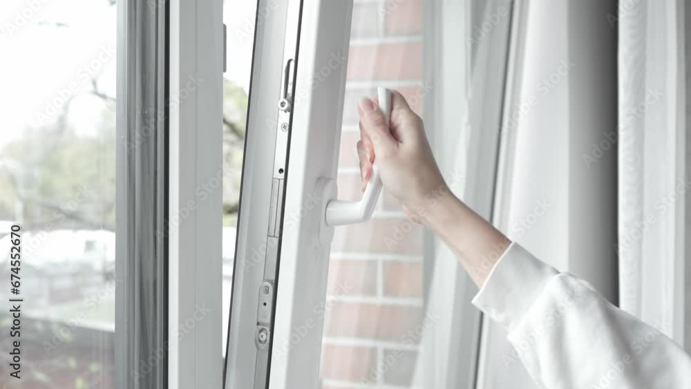 Window Let Open The woman turns the handle of the plastic window frame with her hand ...