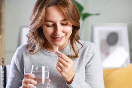 Happy young woman taking vitamins photo