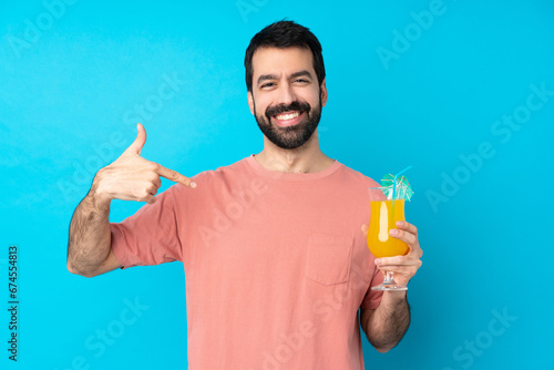 Young man over holding a cocktail over isolated blue background proud and self-satisfied photo