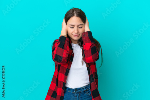 Young Ukrainian woman isolated on blue background frustrated and covering ears