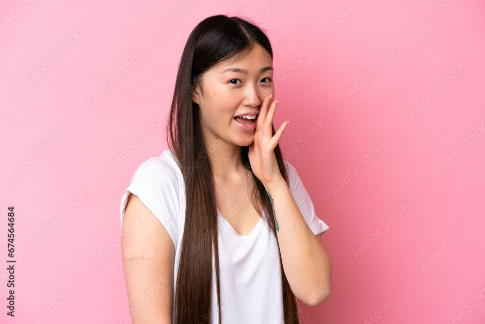Young Chinese woman wearing a band aids isolated on pink background shouting with mouth wide open Young Chinese woman wearing a band aids isolated on pink background shouting with mouth wide open