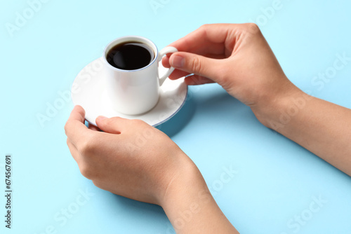 Woman holding cup of hot coffee on blue background