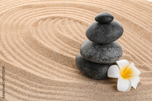 Stack of zen stones with white flower on sand. Harmony with nature concept