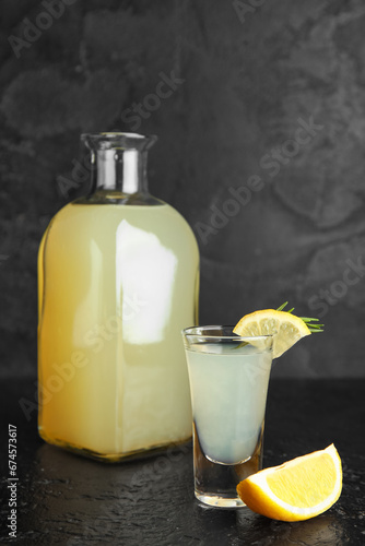 Bottle and shot of tasty Limoncello with rosemary on black background