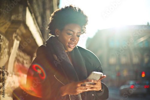 young black woman uses a smartphone on the street photo