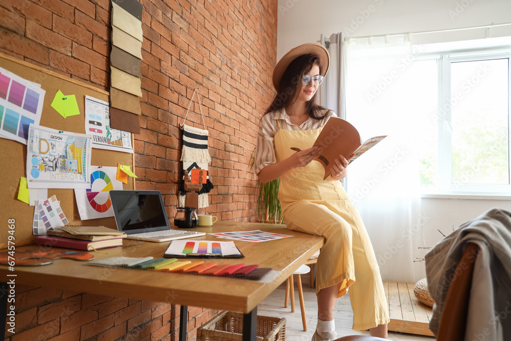 Female interior designer with magazine working in office