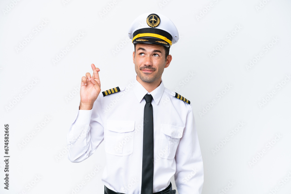 Airplane pilot over isolated white background with fingers crossing and wishing the best Airplane pilot over isolated white background with fingers crossing and wishing the best