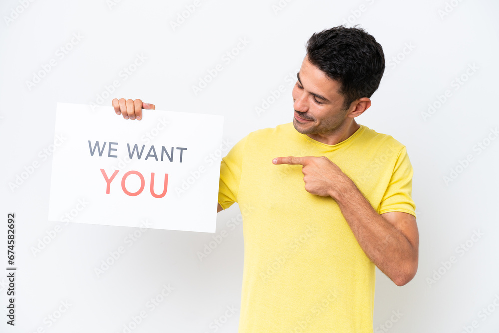 Young handsome man over isolated white background holding We Want You board and pointing it Young handsome man over isolated white background holding We Want You board and pointing it