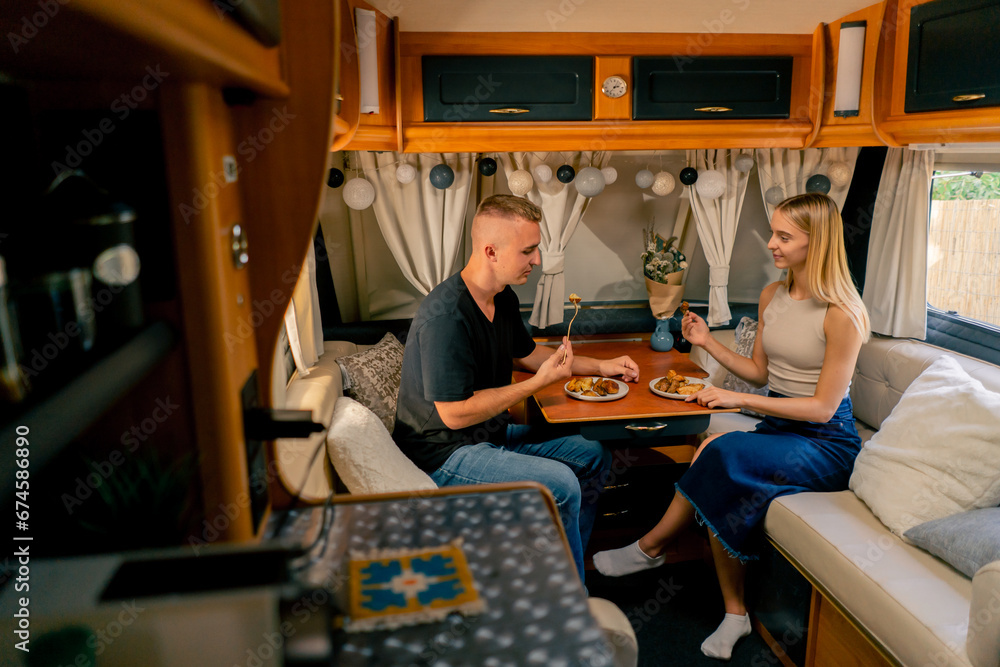 Couple in love together on a date in a mobile home sitting at the table and having dinner in romantic setting