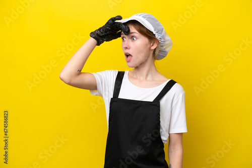 Young English fisherwoman isolated on yellow background doing surprise gesture while looking to the side