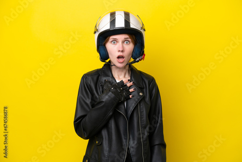 Young English woman with a motorcycle helmet isolated on yellow background surprised and shocked while looking right