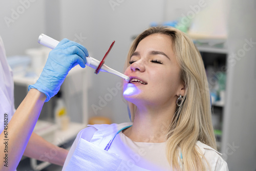 young girl on a teeth whitening treatment, using ultraviolet lamp for bleaching