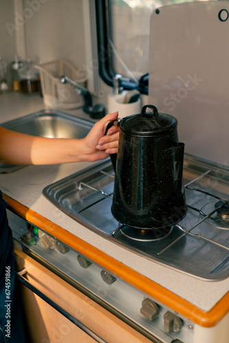Close-up shot of a woman's hand putting a kettle on gas stove to heat water for brewing tea with boiling water
