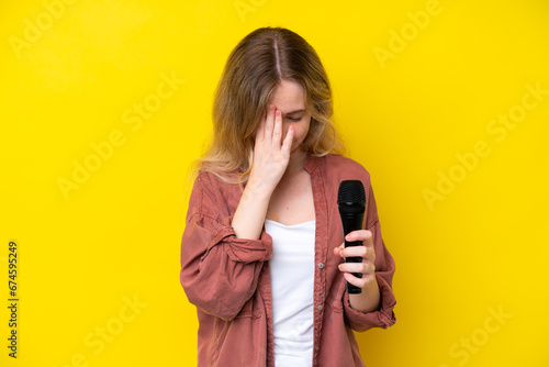 Quadro su tela Young singer caucasian woman picking up a microphone isolated on yellow backgrou