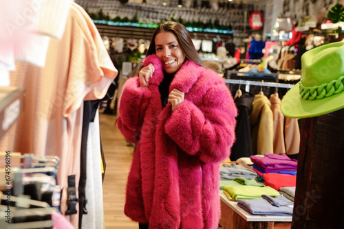Young woman in fur coat choosing winter clothes in a clothing store. © zorandim75