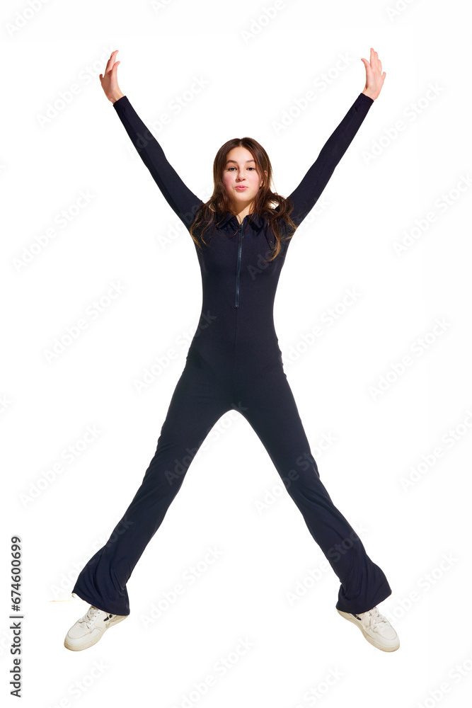 Happy young beautiful girl, teenager dressed in black overall jumping in star shape isolated white studio background. Concept of beauty, youth, human emotions, fashion, style, modelling. Ad
