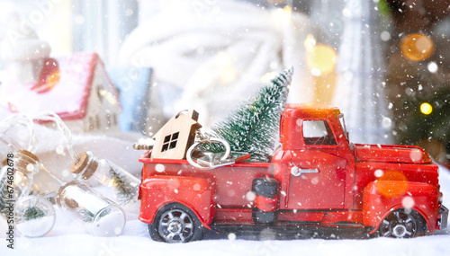 Red retro car with a Christmas tree decorates with the house key in the pickup truck for Christmas. Buying a home, moving, mortgage, loan, real estate, festive mood, New Year