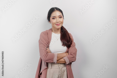 A confident smiling Asian woman employee wearing cardigan standing with arms folded and looking at the camera isolated over white background photo