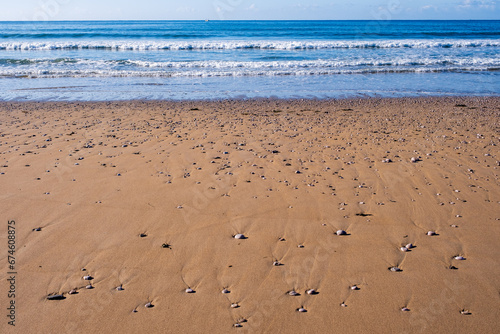Sandy beach with pebbles with gentle blue sea behind